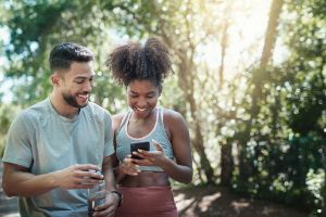 Mann und Frau in Sportklamotten schauen auf ein Handy